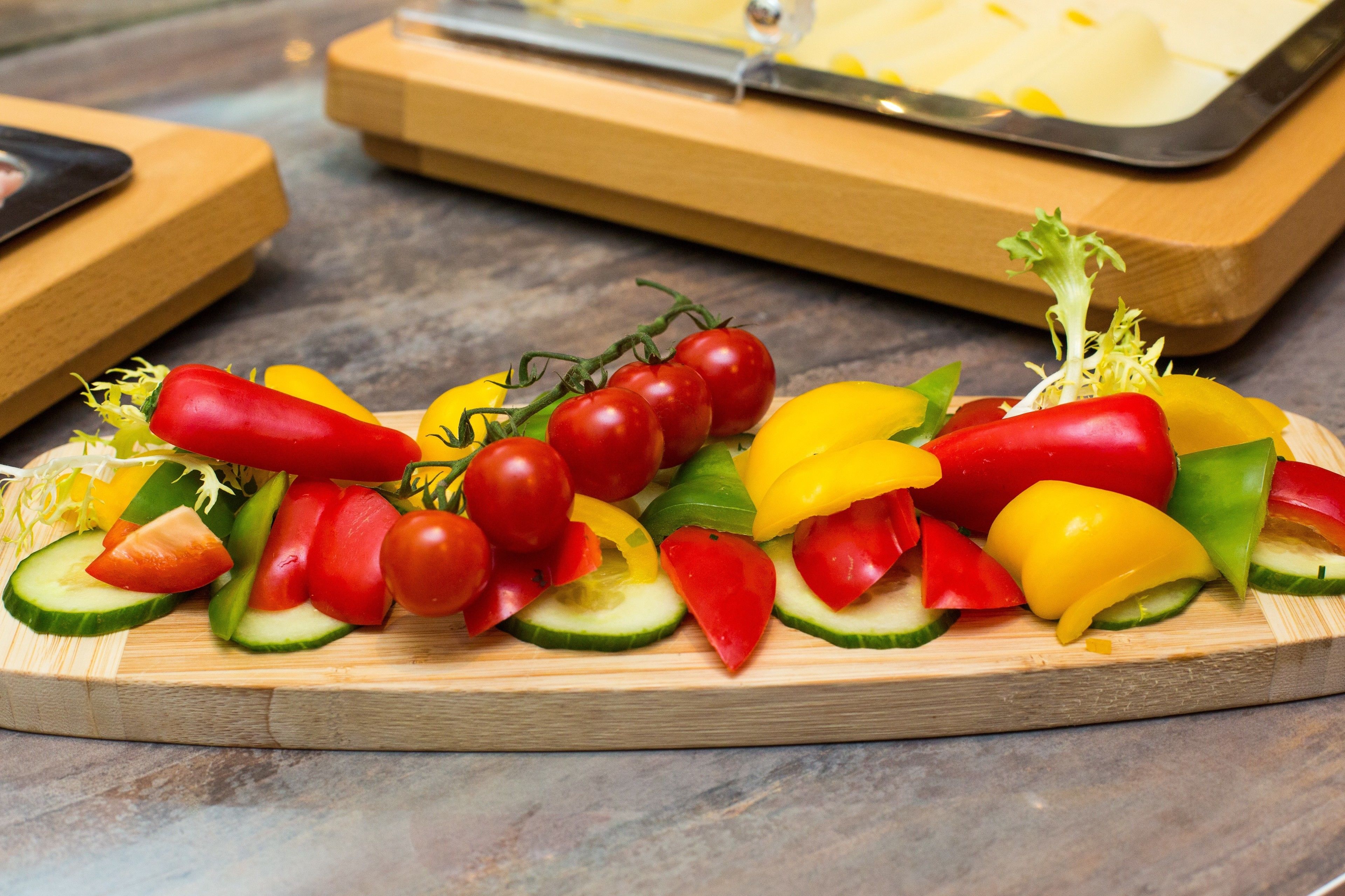 Una tabla de madera con una variedad de verduras en rodajas, como pepinos, tomates y pimientos.