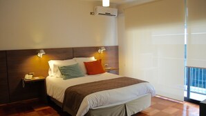 A hotel room with a large bed, two bedside lamps, a nightstand with a phone, and a view of the outside through a large window. - Hotel Santa Lucia (Santiago)