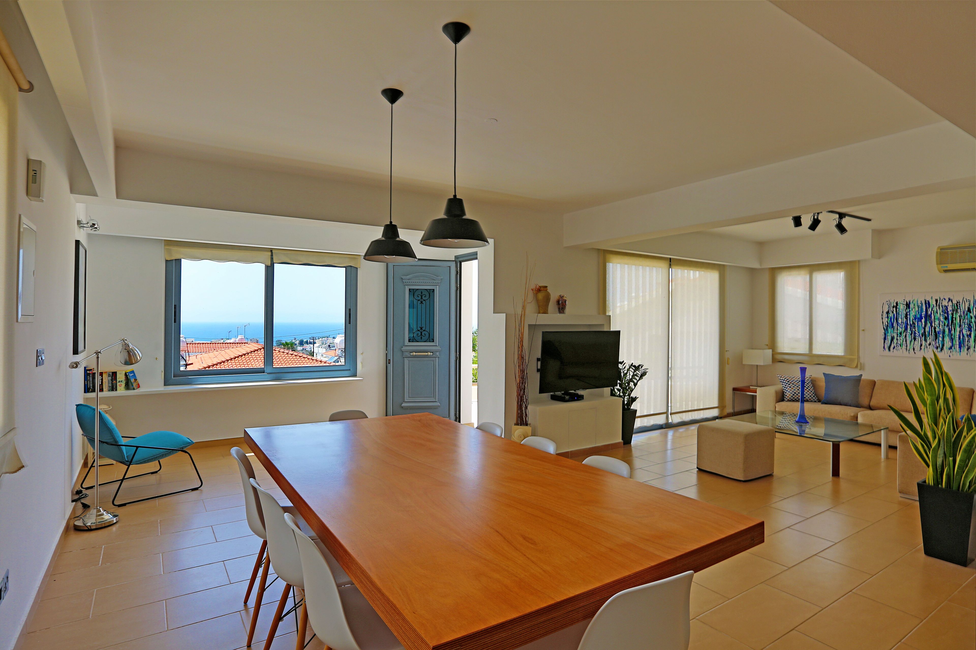 Un'ampia zona giorno con un tavolo da pranzo in legno, una TV e un divano.