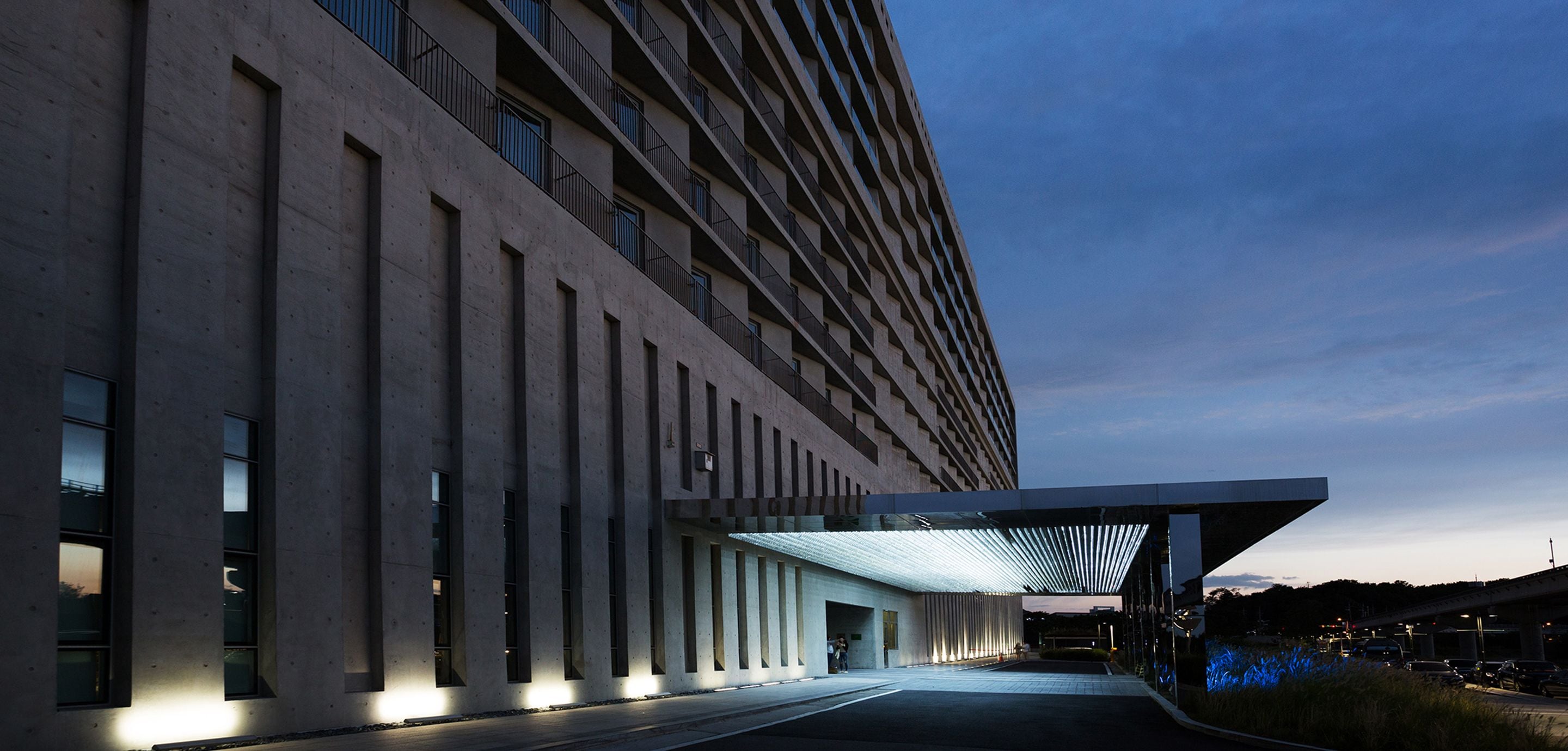 Un bâtiment moderne à la façade plate, doté de grandes fenêtres et d’un espace d’entrée abrité.