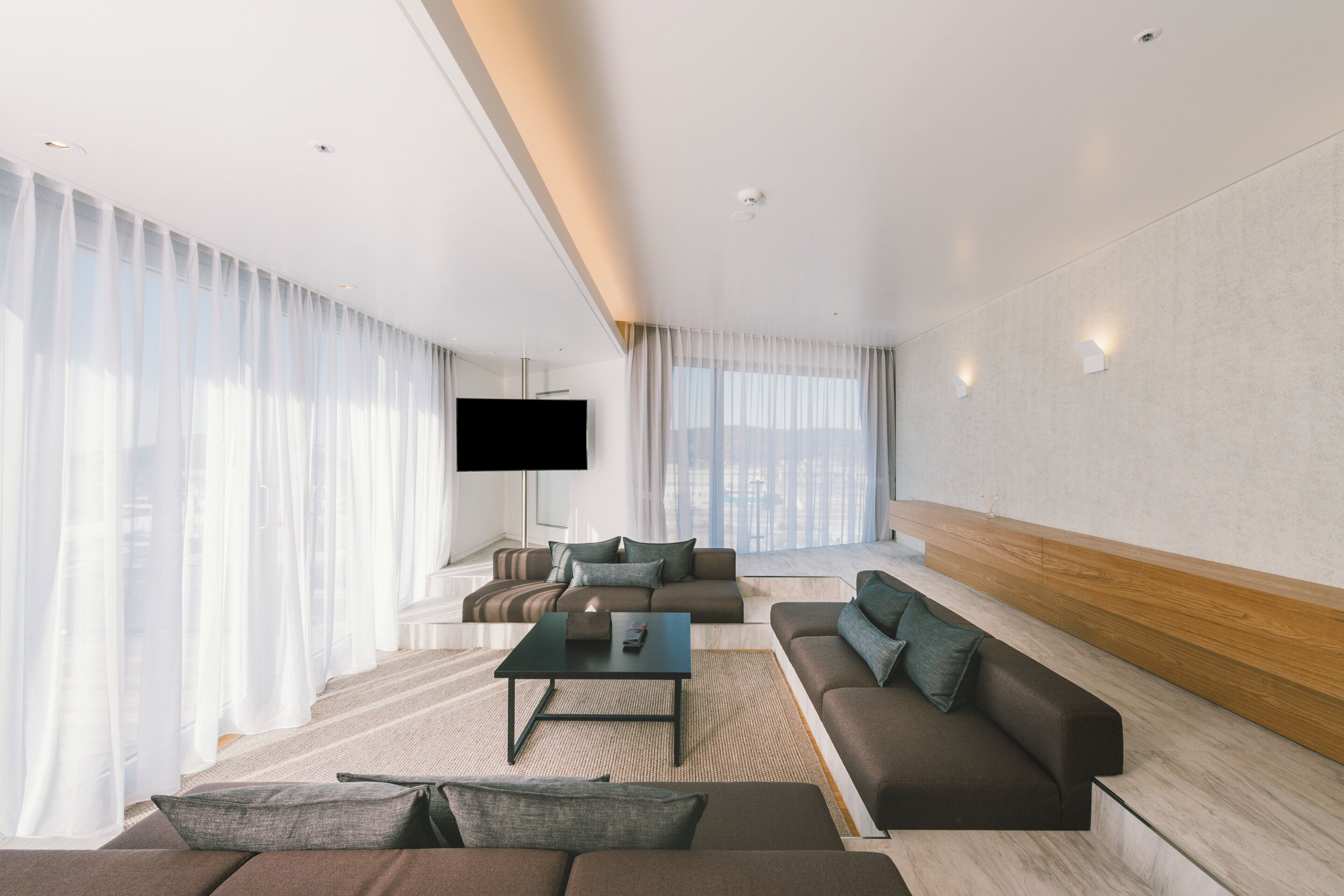 Een moderne woonkamer met een zithoek, een salontafel en een flatscreen televisie aan de muur.