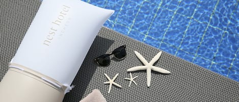 Una toalla de playa, una botella, gafas de sol y estrellas de mar junto a una piscina.