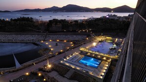 A resort with a swimming pool, sun loungers, and a view of the sea.