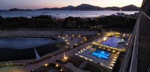 A resort with a swimming pool, sun loungers, and a view of the sea.