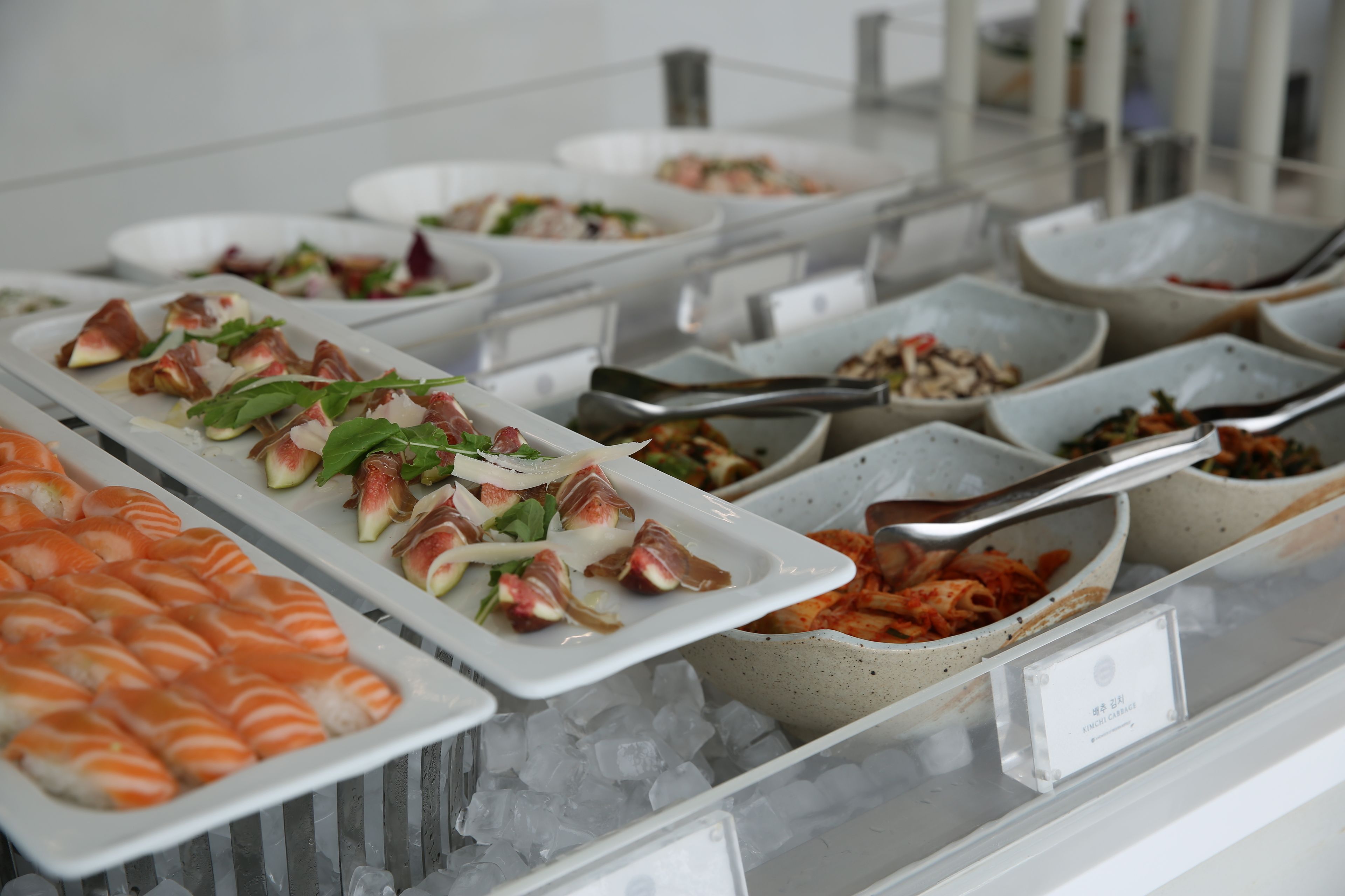 A buffet with various dishes including sushi, salads, and other prepared foods.