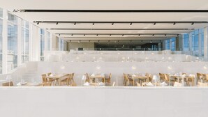 A modern restaurant with a spacious interior, featuring high ceilings, large windows, and a clean, minimalist design.
