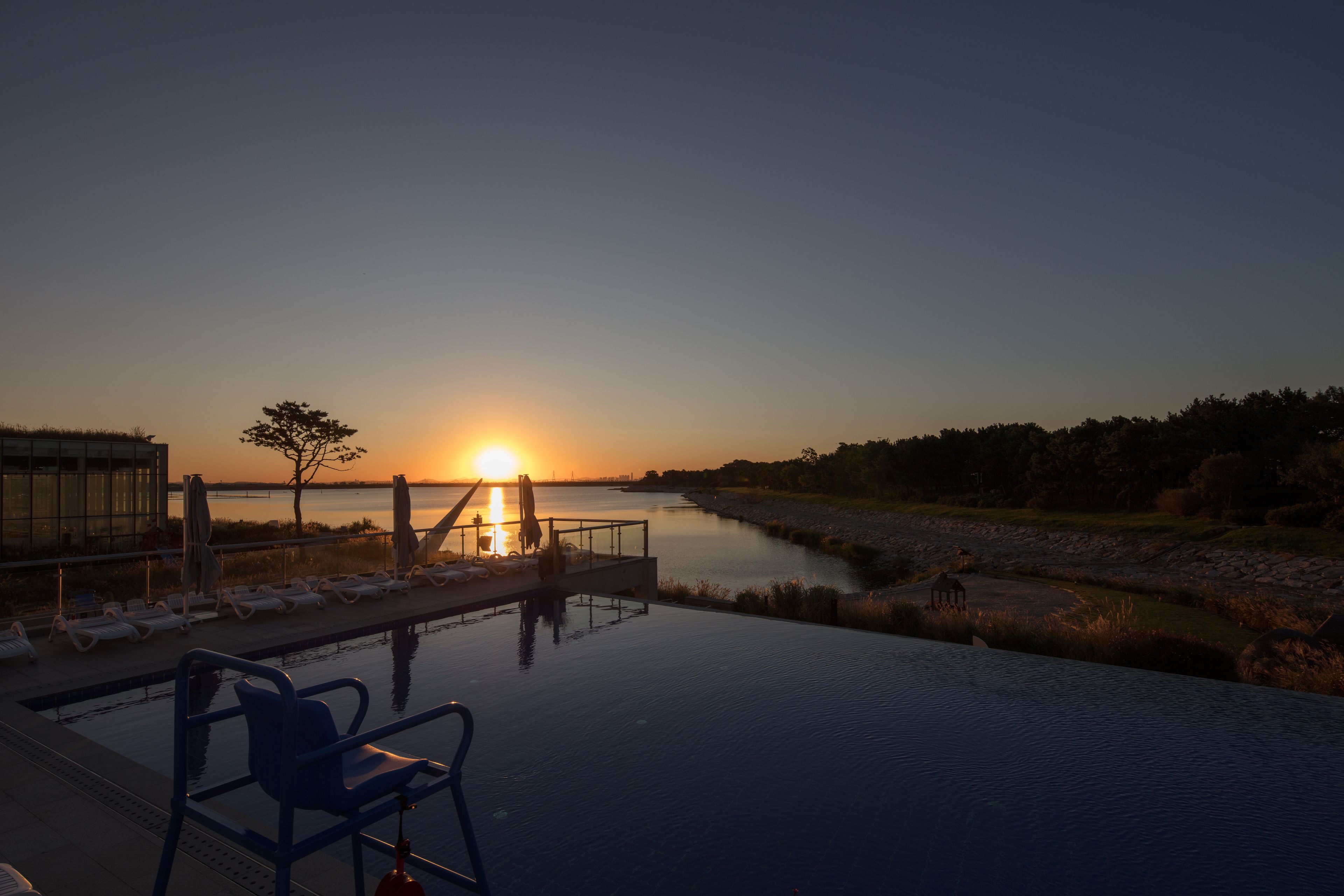 Una piscina a sfioro con lettini e vista sul tramonto.