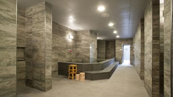 A modern lobby with marble walls, a reception desk, and a wooden stool.