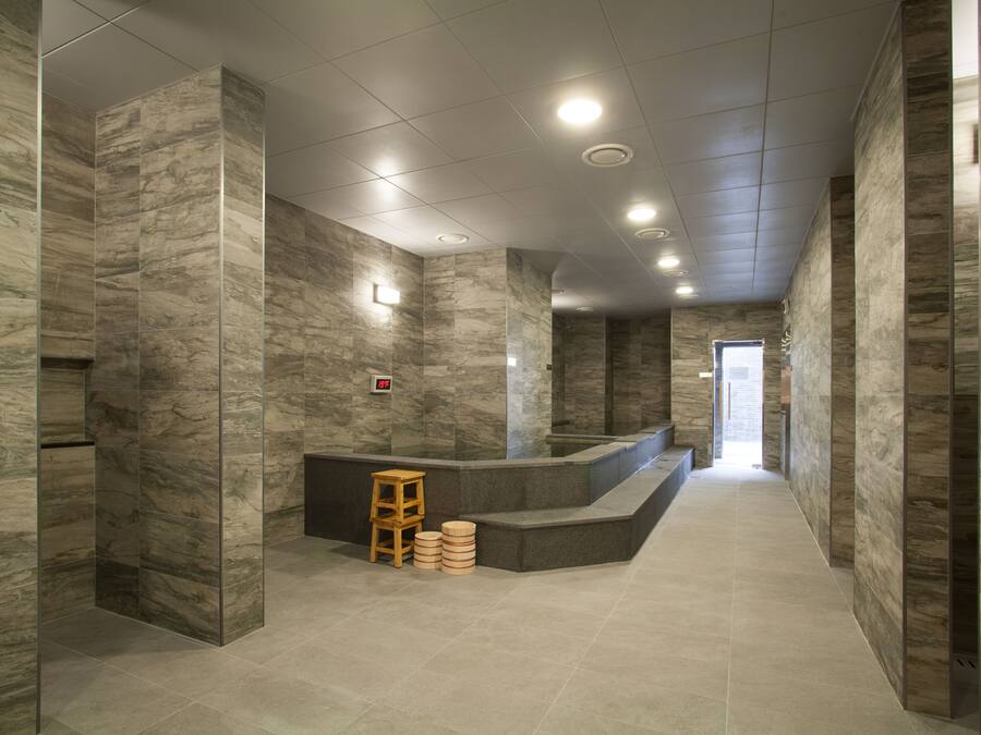 A modern lobby with marble walls, a reception desk, and a wooden stool.