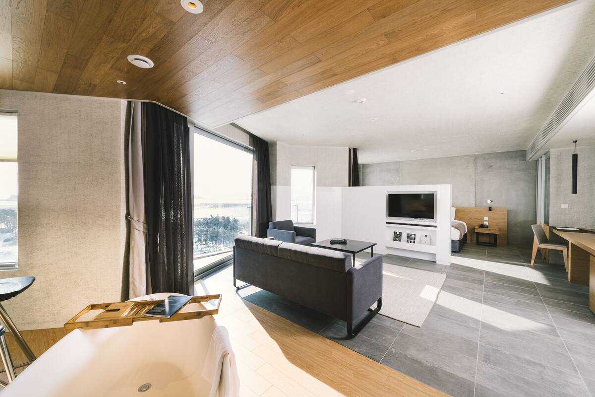 A modern living room with a sofa, TV, and dining area.