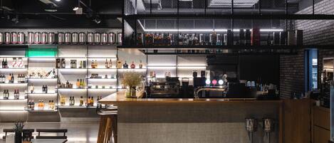 Un área de bar moderna con una barra alta, estantes con botellas y una máquina de café.
