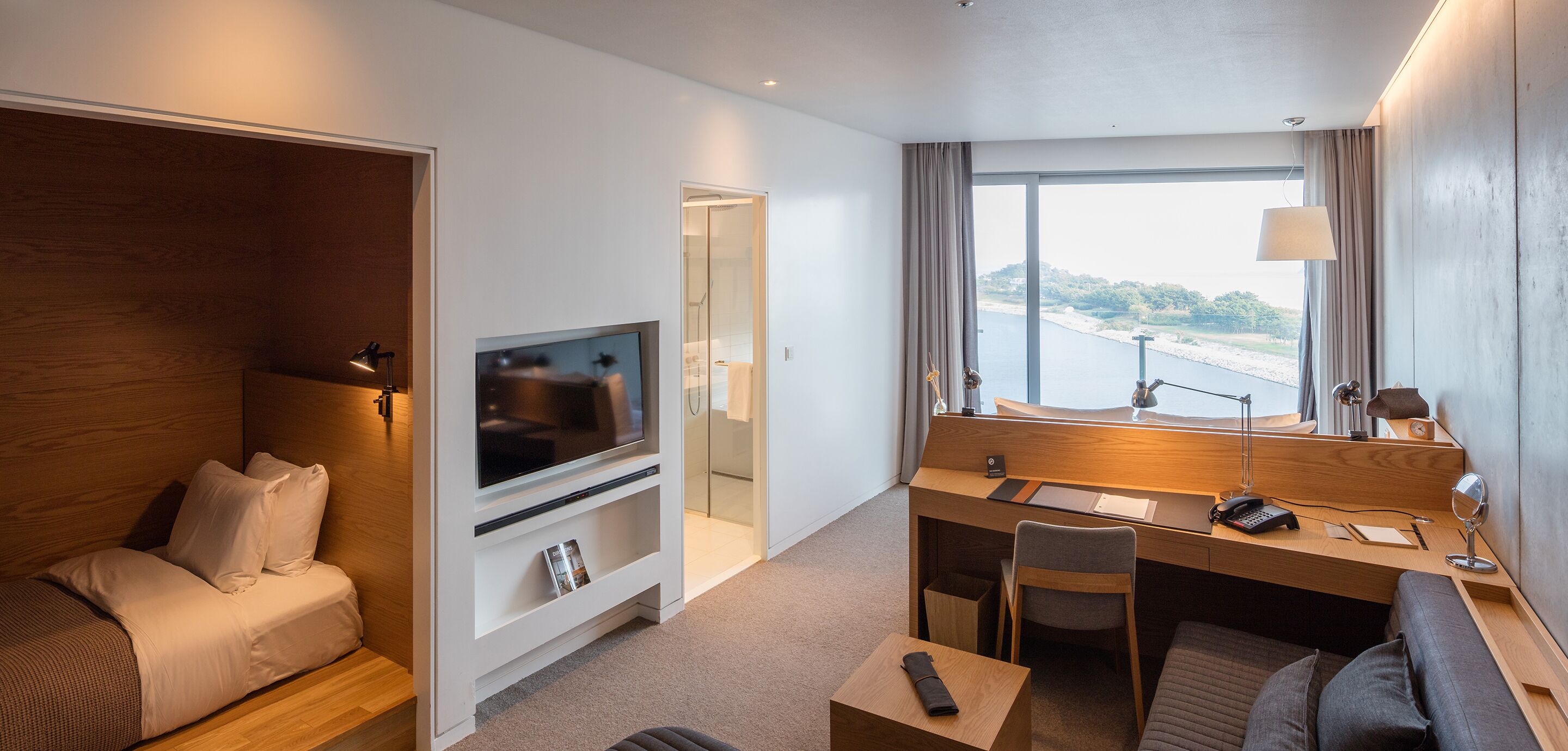Habitación de hotel con cama, televisión, escritorio y vista al mar.