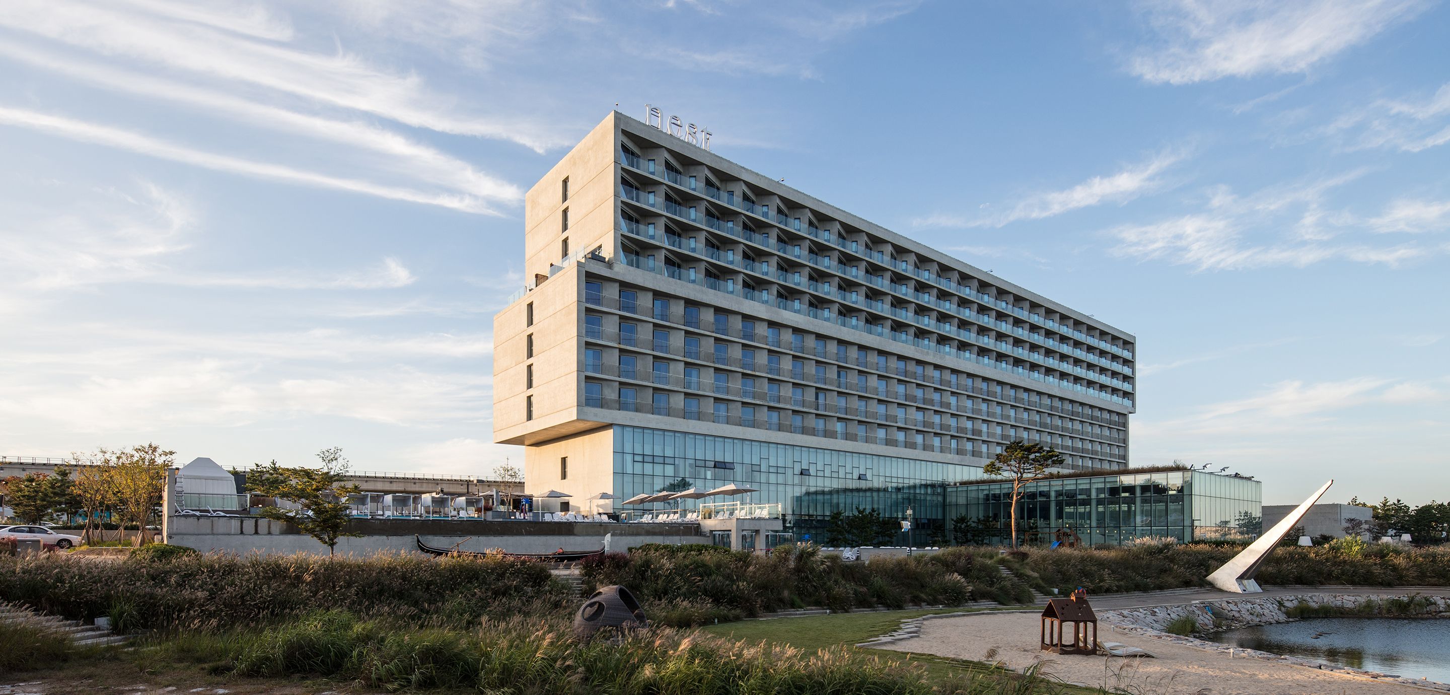 A modern hotel with a flat roof, multiple floors, and a glass facade.
