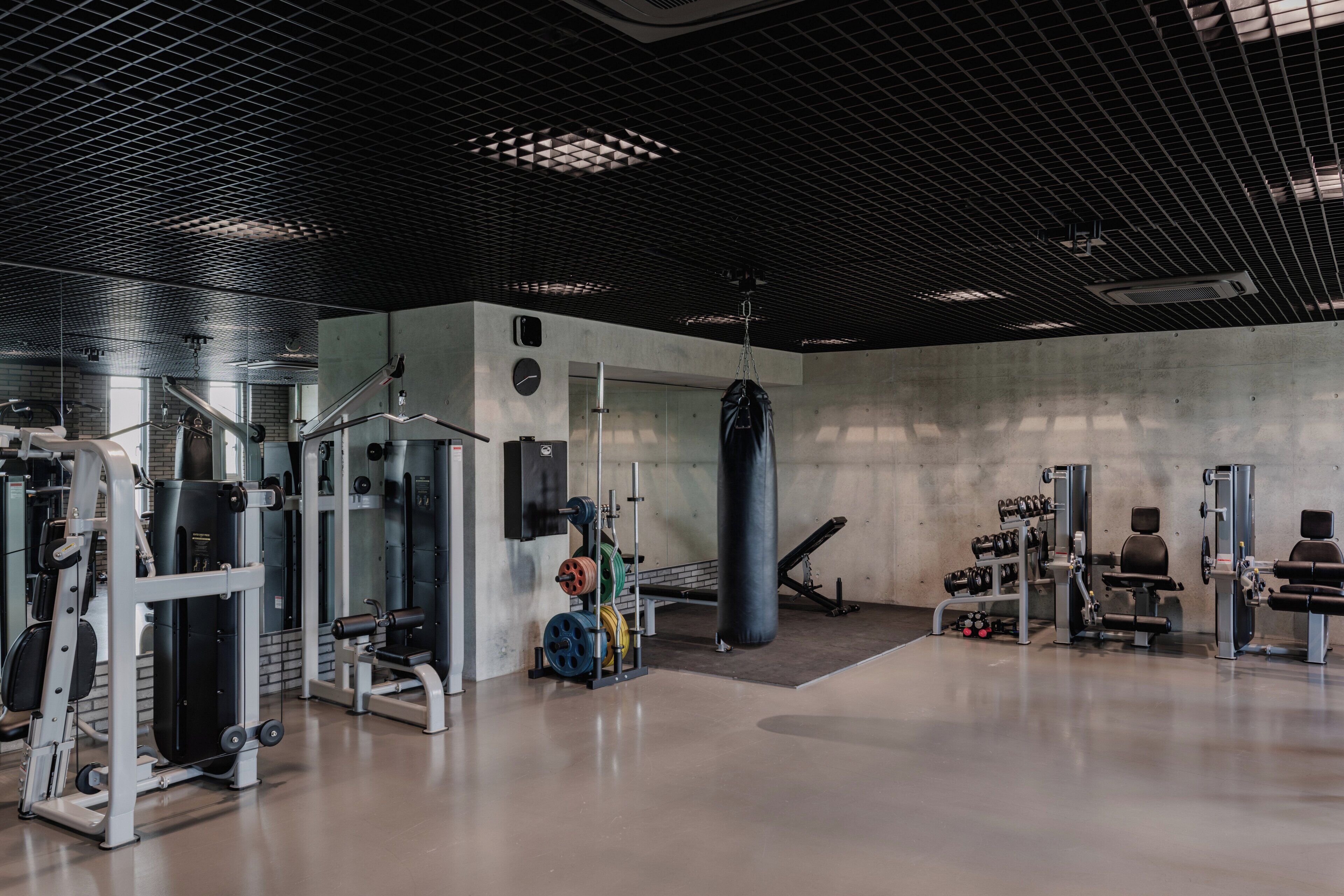 A gym with various exercise equipment, including weight machines and a punching bag.