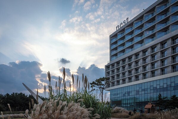 A modern hotel building with a glass facade and multiple balconies.