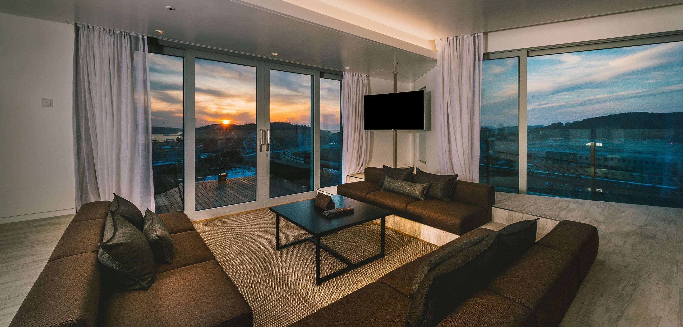 A modern living room with a sofa, coffee table, and a TV mounted on the wall.