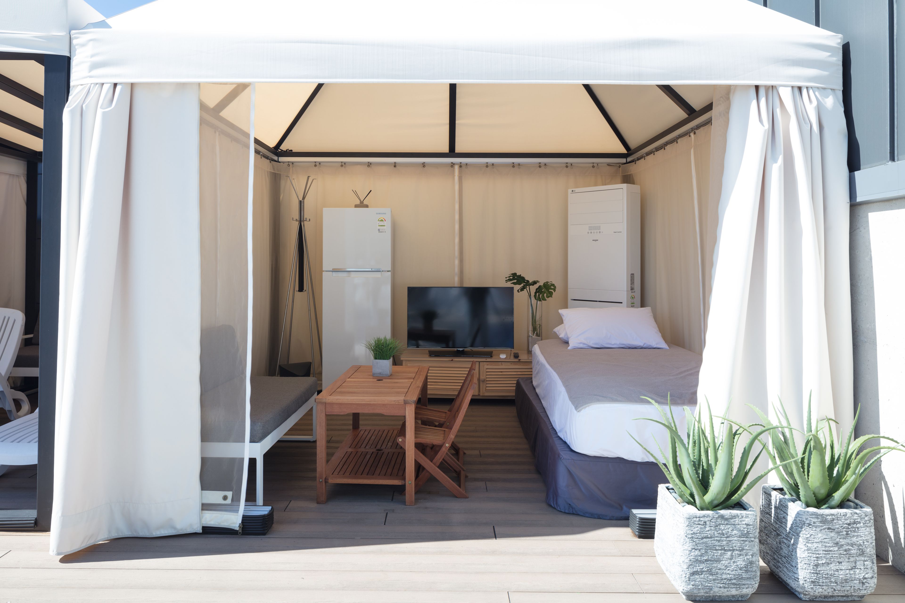 A compact room with a bed, a TV, a small table, and a chair.