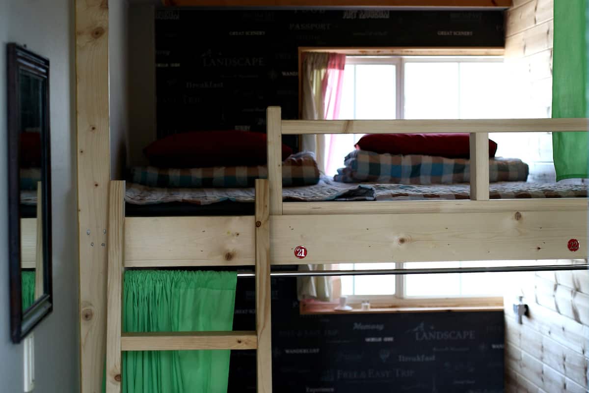 Une chambre avec des lits superposés, un plafond en bois et un mur recouvert d’un tableau noir.