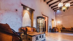 Una habitación espaciosa con un cofre de madera, sillones de cuero y un sofá.