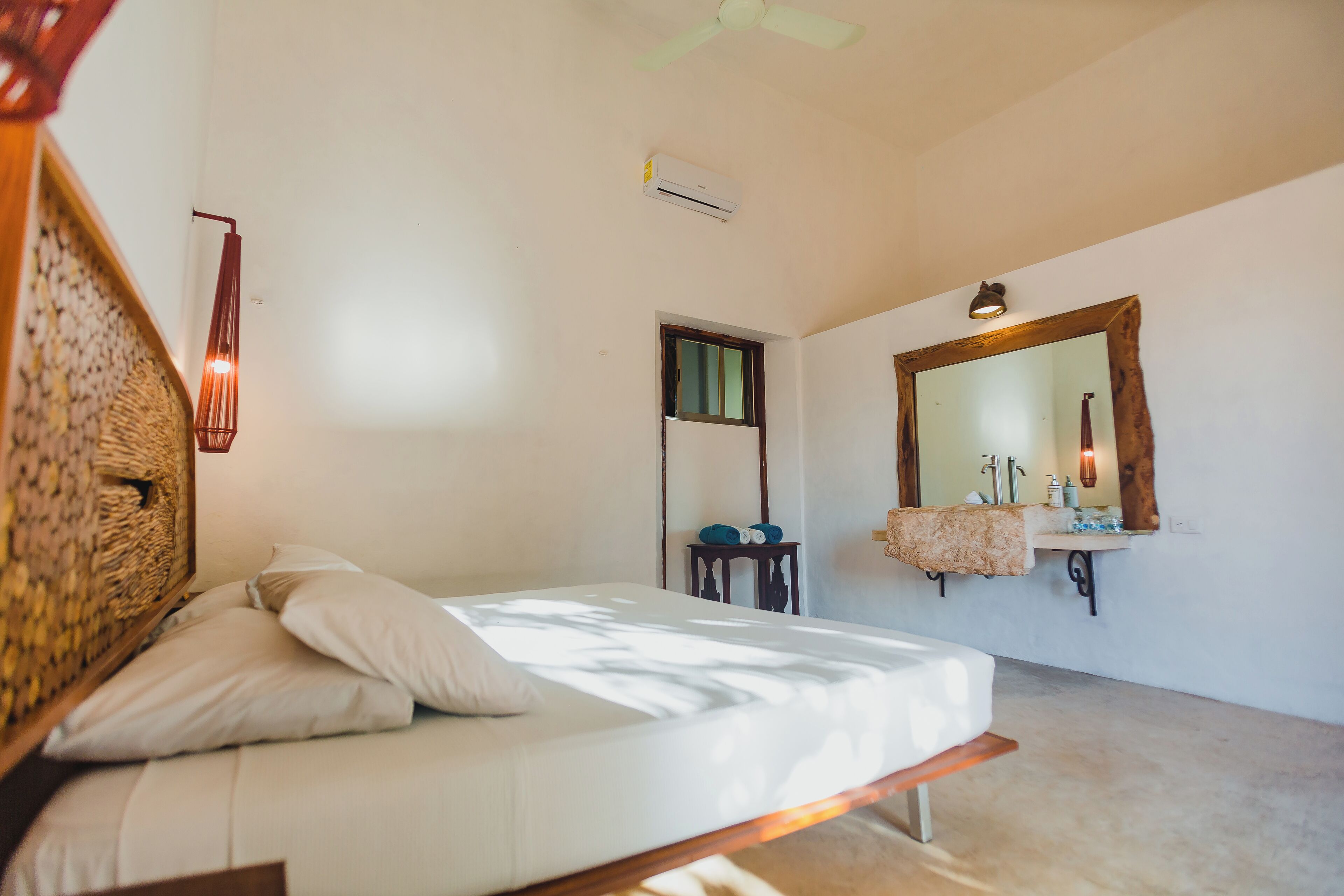 Une chambre à coucher avec un lit, une table de chevet, un miroir et une fenêtre.