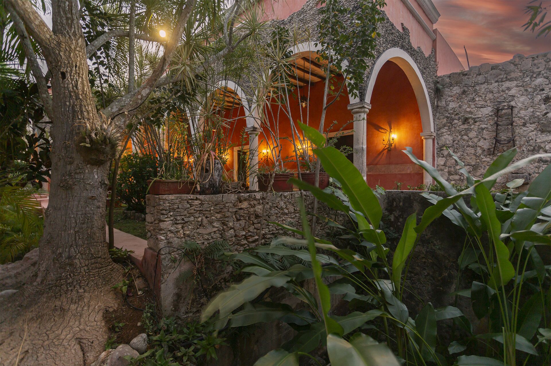 Un edificio tradicional con arcos y paredes de piedra, rodeado de abundante vegetación.