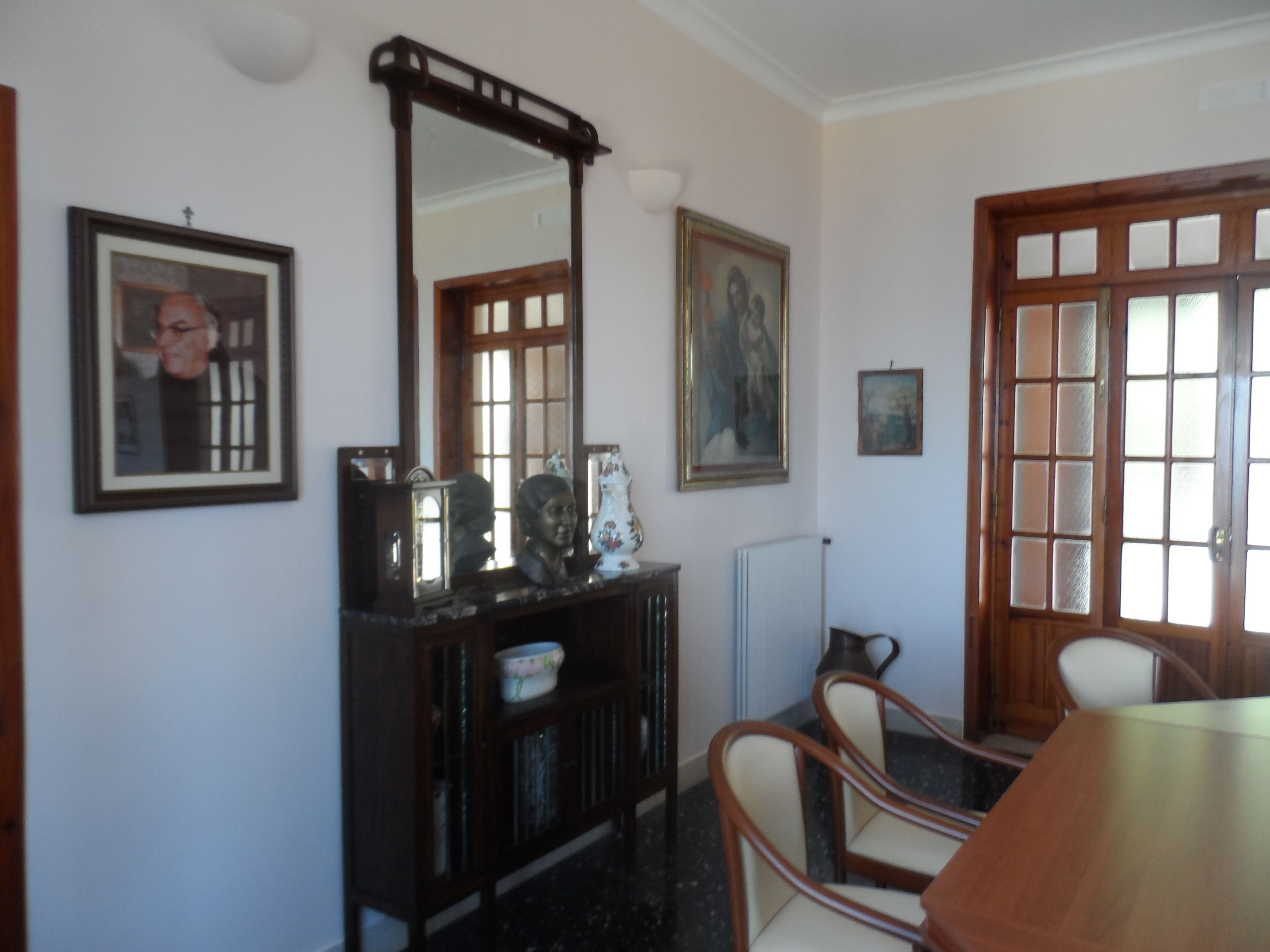 A dining area with a wooden table and chairs, a large mirror, and framed artwork on the walls.