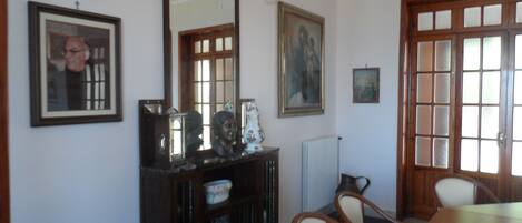 A dining area with a wooden table and chairs, a large mirror, and framed artwork on the walls.