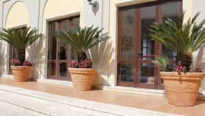 Un bâtiment doté de grandes fenêtres et de grandes portes, de plantes en pot et d’un hall d’entrée carrelé.