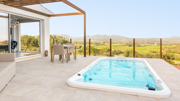 Ein moderner Poolbereich im Freien mit Whirlpool, Esstisch und Stühlen mit Blick auf eine schöne Landschaft.