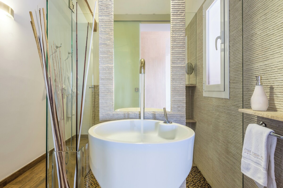 Ein modernes Badezimmer mit einer großen weißen Badewanne, einer Duschkabine aus Glas und einem Spiegel über dem Waschbecken.