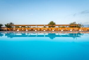 Una piscina al aire libre, una piscina infinita, sombrillas