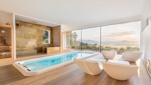 Ein moderner, überdachter Poolbereich mit Blick auf Berge, Holzboden und zeitgemäße Sitzmöbel.
