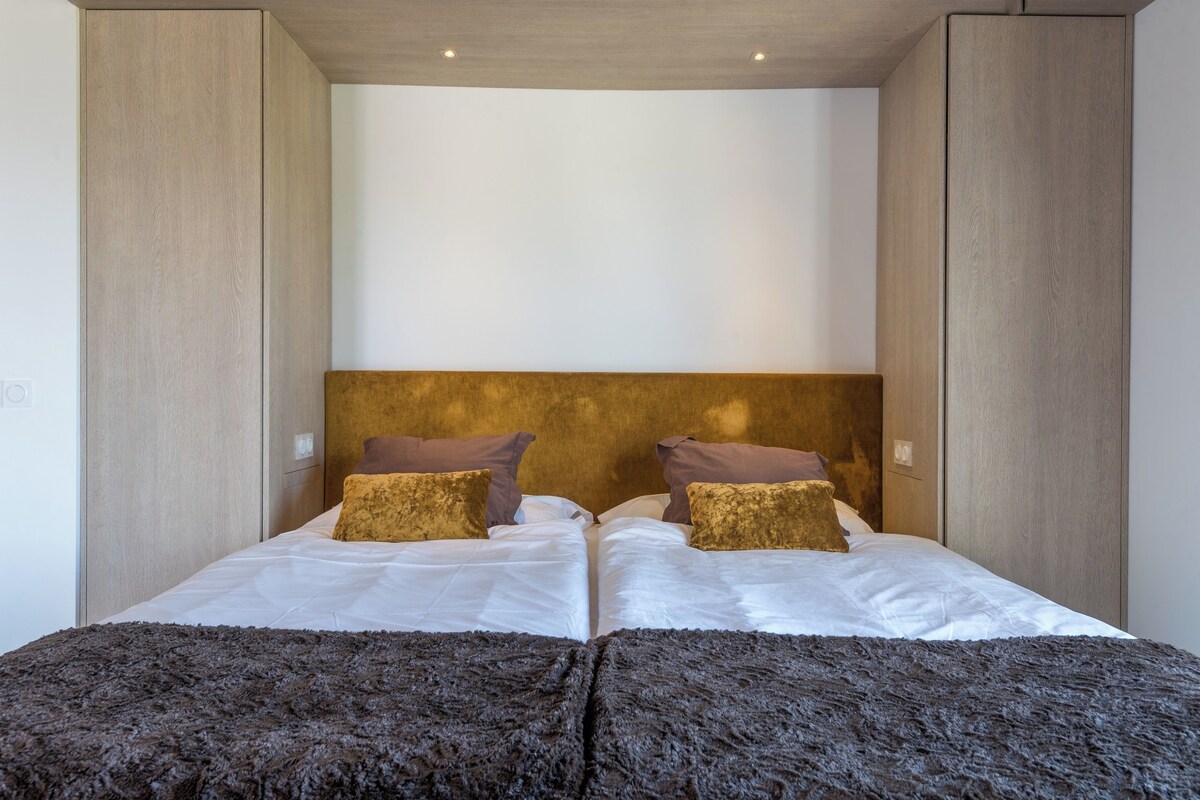 A double bed with two pillows, a headboard, and a dark textured rug.