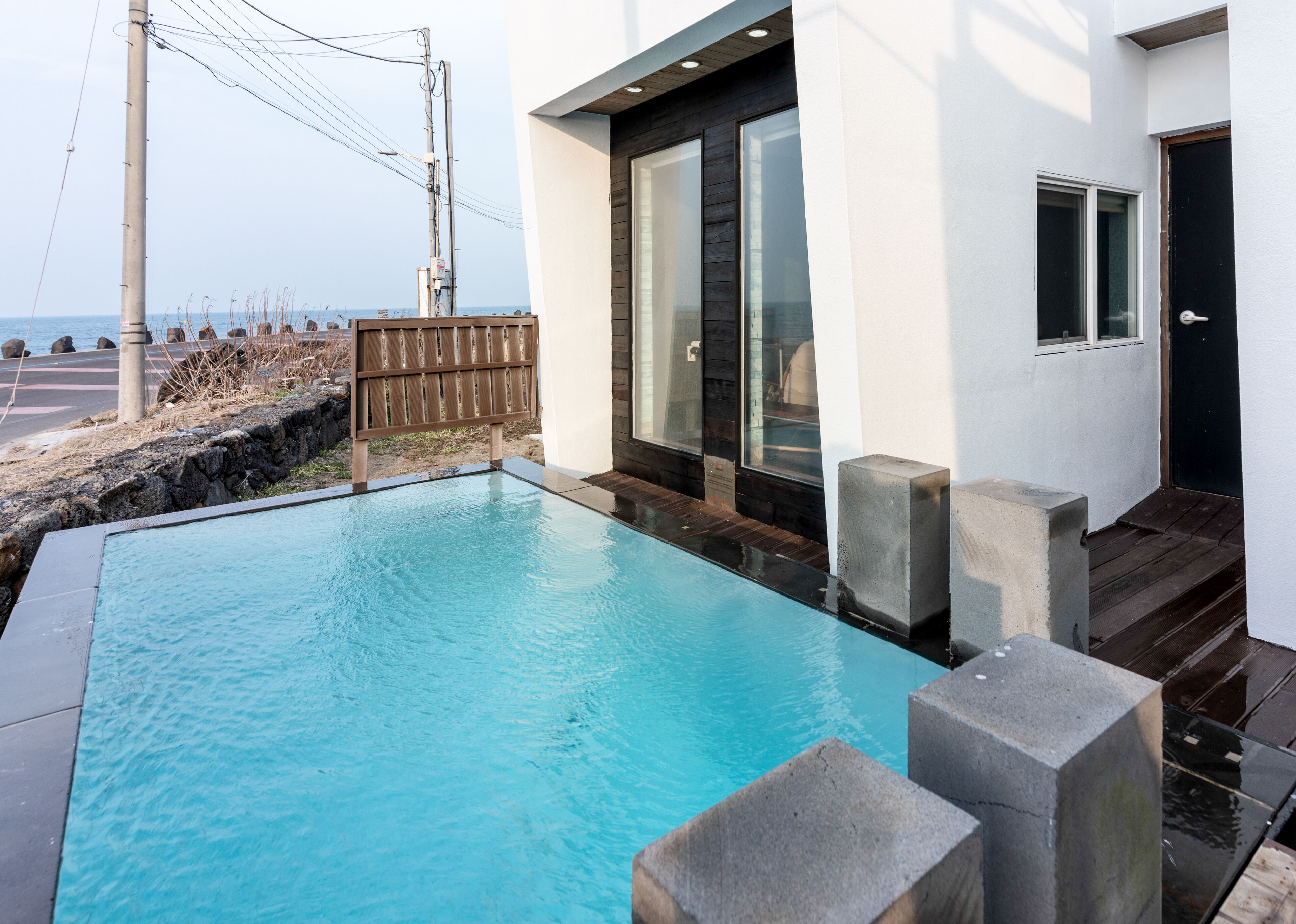 A swimming pool with a wooden deck and a view of the sea.