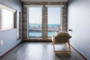 Une chambre dotée d’une grande fenêtre donnant sur une piscine et offrant une vue sur la mer.