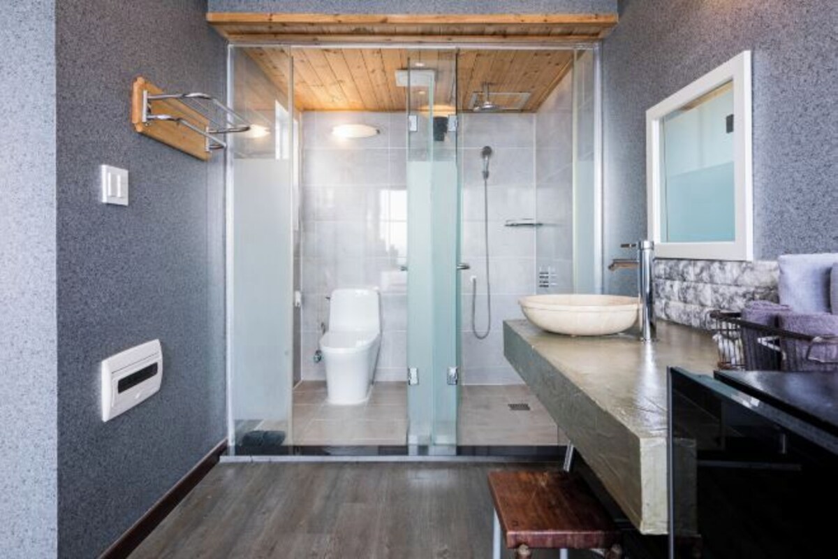 A modern bathroom with a glass shower enclosure, a white toilet, and a marble countertop.