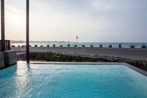 A swimming pool with a view of the sea and a rocky shoreline. - Aqua BEAutique (Jeju City)