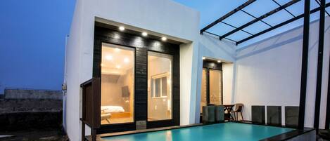 A modern building with a swimming pool, large windows, and a glass ceiling structure.