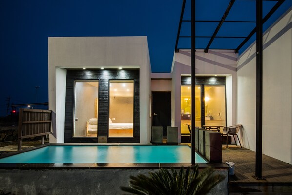 A modern house with a swimming pool, a bedroom with a large window, and a dining area. - Aqua BEAutique (Jeju City)