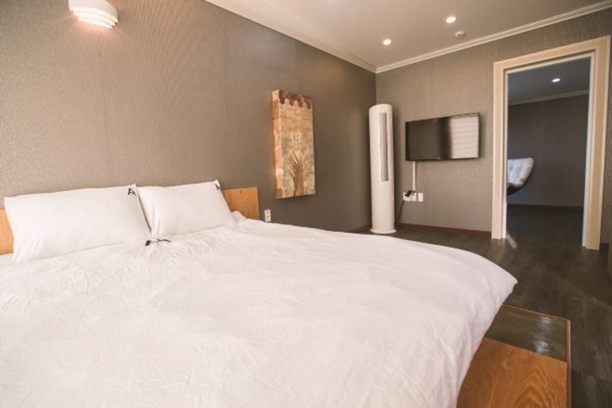 A modern hotel room with a large bed, a flat-screen TV mounted on the wall, and a walk-in closet.