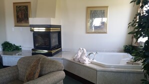 A living room with a sofa, a fireplace, a bathtub, and framed artwork on the walls. - Tamarack Motor Inn (Rocky Mountain House)