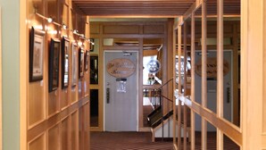 A corridor with a wooden floor and walls, leading to a room labeled "Guest Rooms Banquet Room." - Tamarack Motor Inn (Rocky Mountain House)