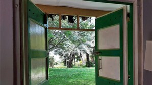 Una porta oberta que dona a una zona verda amb arbres i un cel serè.