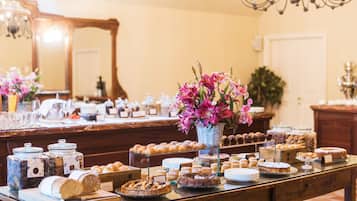 A buffet table with various pastries, cakes, and a floral centerpiece.
