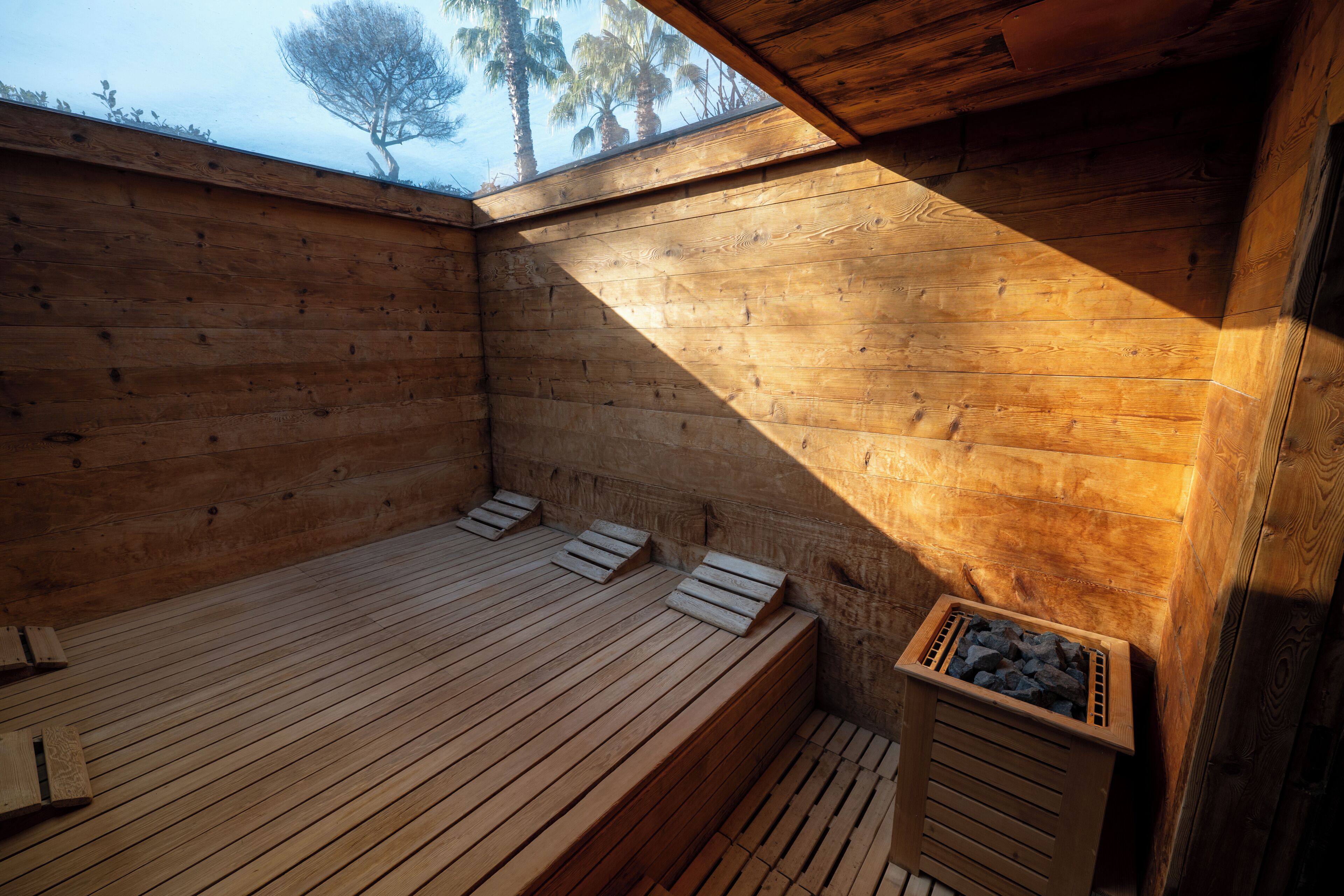 Un sauna en bois avec des bancs et un récipient en pierre.