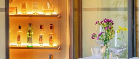 A hotel room with a minibar, a table set with a white tablecloth, and a mirror.