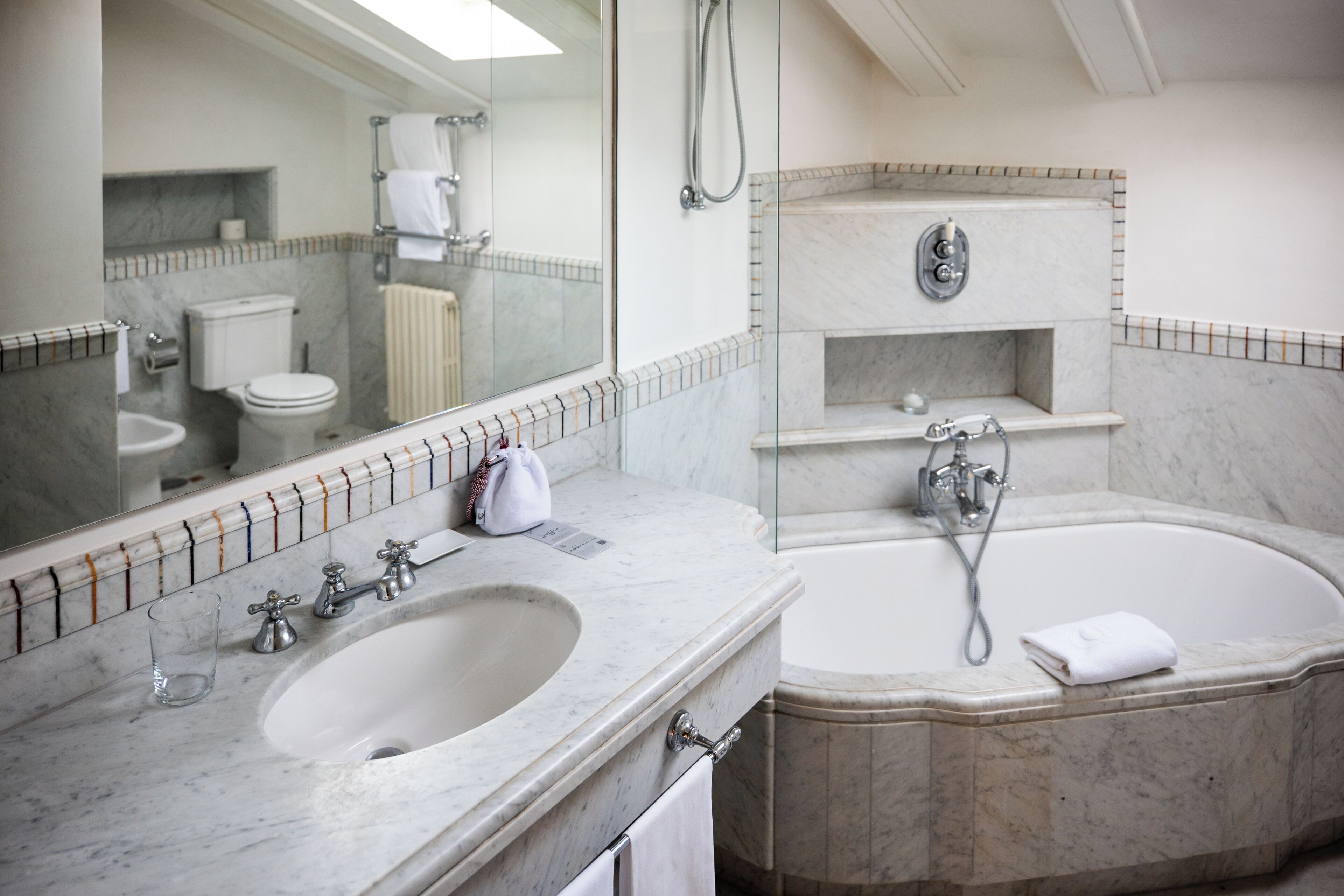 A bathroom with a marble sink, a bathtub, a toilet, and a shower.