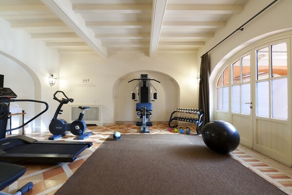A home gym with exercise equipment, a large exercise ball, and a window with curtains.