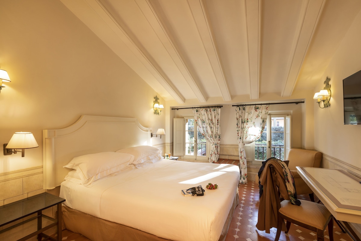 A hotel room with a large bed, a desk, and a chair.