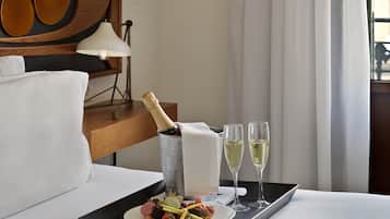 Un plateau avec une bouteille de champagne, deux coupes de champagne et une assiette de dessert posée sur un lit.